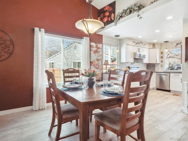 dining space with light wood-style floors, a healthy amount of sunlight, and baseboards