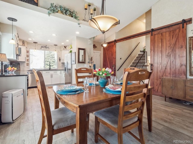 dining space with light wood finished floors, a barn door, and recessed lighting