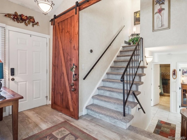 foyer featuring light wood-type flooring, a barn door, and stairway