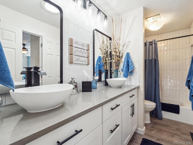 full bathroom featuring double vanity, wood finished floors, a sink, and toilet