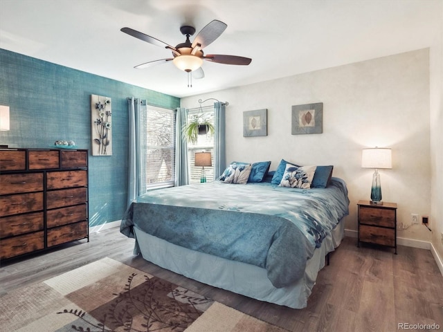 bedroom with ceiling fan, wood finished floors, and baseboards