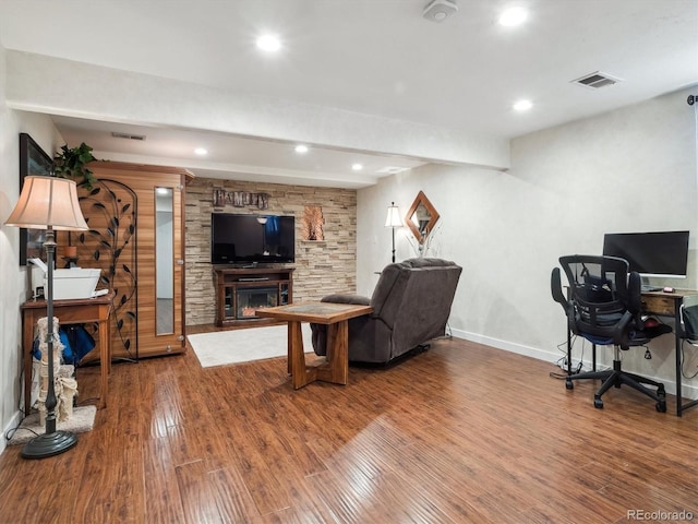 living area with a fireplace, wood finished floors, visible vents, baseboards, and beamed ceiling