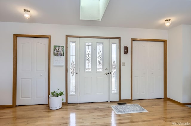 foyer featuring light wood-style floors, baseboards, and a wealth of natural light