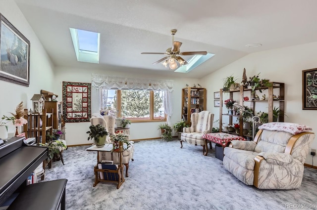 living area featuring lofted ceiling with skylight, carpet flooring, baseboards, and a ceiling fan