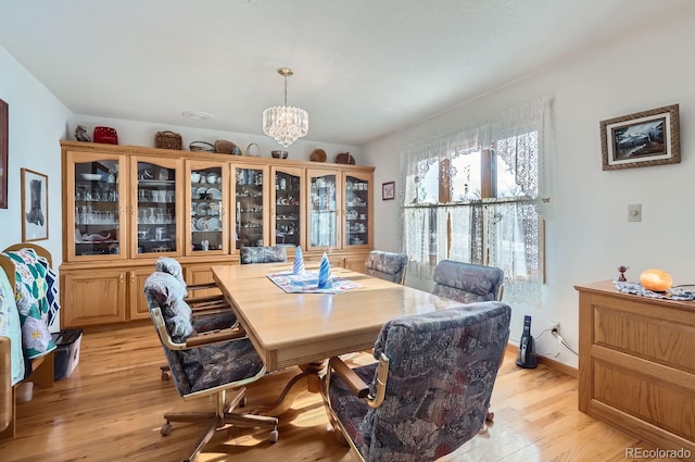 dining space featuring light wood finished floors, baseboards, and a chandelier