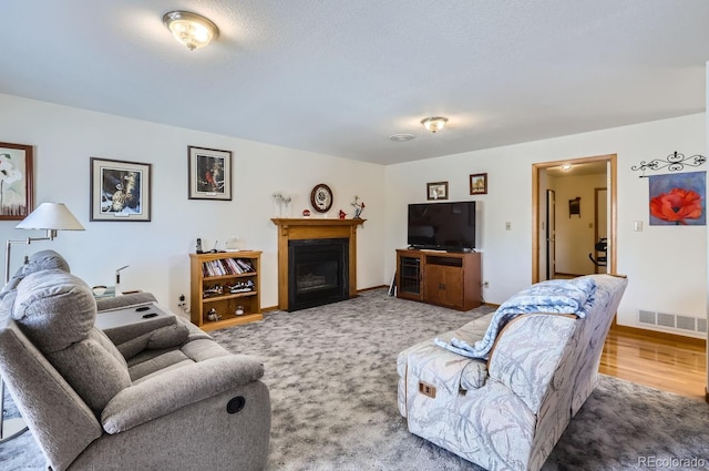 living area with light carpet, a glass covered fireplace, visible vents, and baseboards