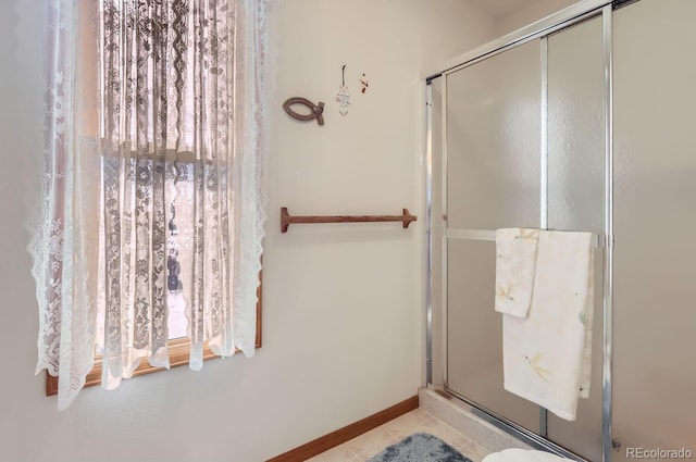 bathroom with a shower stall and baseboards