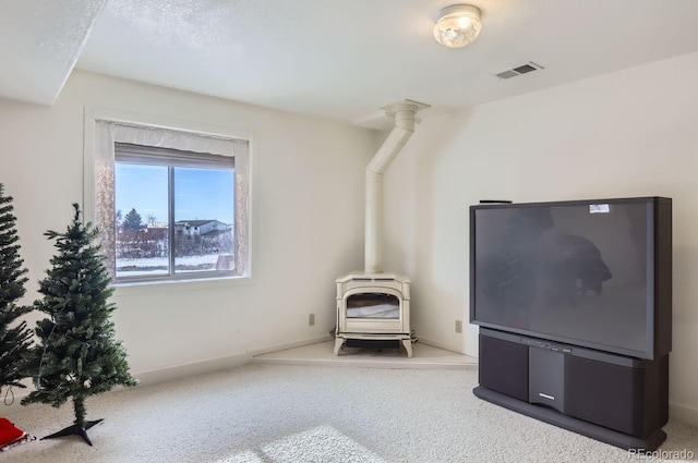 interior space featuring carpet floors, a wood stove, visible vents, and baseboards