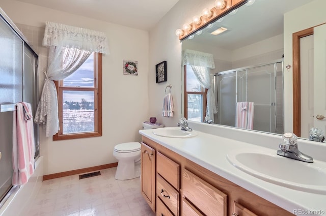 bathroom with a shower with door, visible vents, and a sink