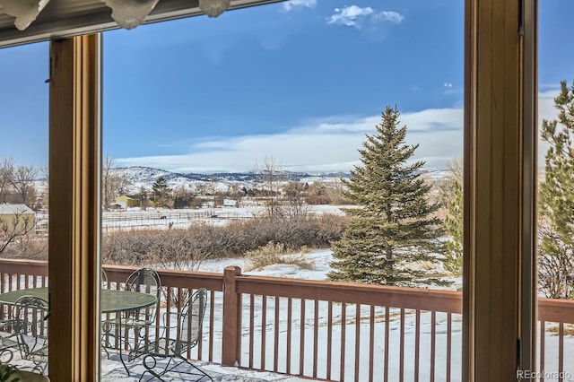snow covered deck with outdoor dining space and a mountain view
