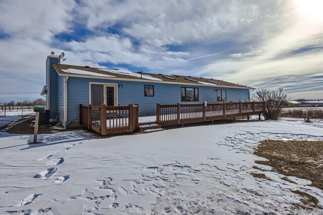 snow covered rear of property featuring a chimney and a wooden deck