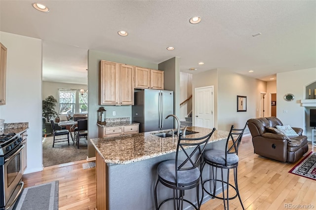 13962 Dexter Way, Thornton, CO 80602 - kitchen with light brown cabinetry, appliances with stainless steel finishes, light wood finished floors, open floor plan, and light stone counters