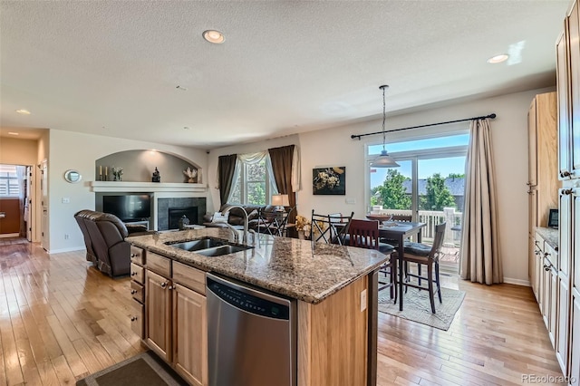 13962 Dexter Way, Thornton, CO 80602 - kitchen with stainless steel dishwasher, light wood-style floors, dark stone countertops, an island with sink, and open floor plan