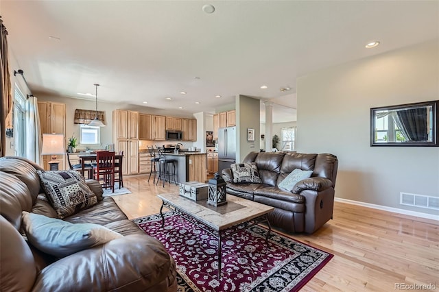 13962 Dexter Way, Thornton, CO 80602 - living area featuring healthy amount of natural light, recessed lighting, light wood-type flooring, and decorative columns