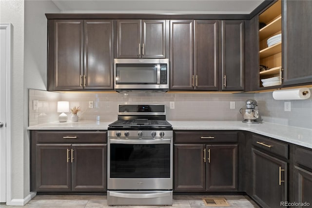 kitchen with tasteful backsplash, dark brown cabinets, light stone countertops, and appliances with stainless steel finishes