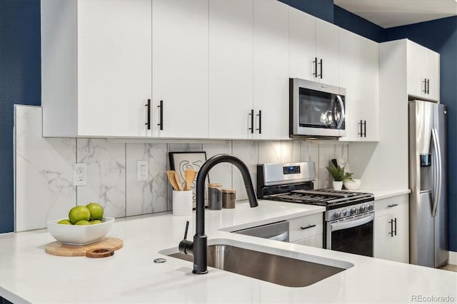 kitchen with decorative backsplash, stainless steel appliances, white cabinets, and sink