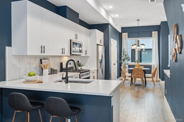 kitchen featuring white cabinets, sink, hanging light fixtures, appliances with stainless steel finishes, and a chandelier