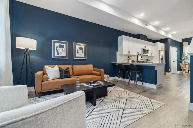 living room with light hardwood / wood-style floors and sink