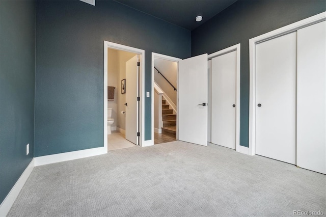 unfurnished bedroom featuring light carpet, ensuite bathroom, and a closet