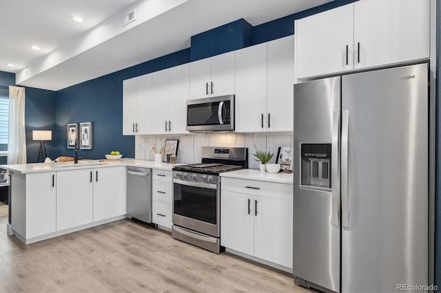 kitchen featuring stainless steel appliances, light countertops, light wood-style floors, and a peninsula