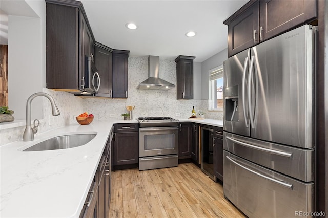 4451 Eliot St, Denver, CO 80211 - kitchen featuring appliances with stainless steel finishes, wall chimney exhaust hood, light wood-style flooring, dark brown cabinets, and recessed lighting