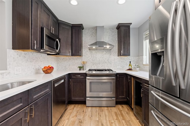 4451 Eliot St, Denver, CO 80211 - kitchen with stainless steel appliances, wall chimney range hood, light wood-style floors, dark brown cabinets, and light countertops