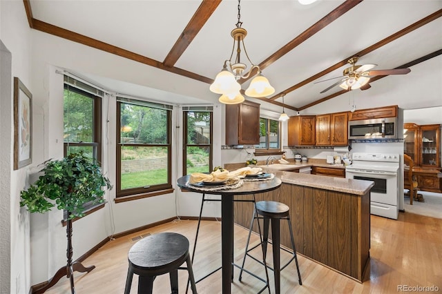 4677 S Wolff St, Denver, CO 80236 - kitchen with white electric range, stainless steel microwave, healthy amount of natural light, and a peninsula