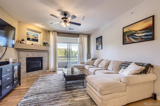 8445 S Holland Way Unit 205, Littleton, CO 80128 - living area featuring a ceiling fan, wood finished floors, a tile fireplace, and a textured ceiling