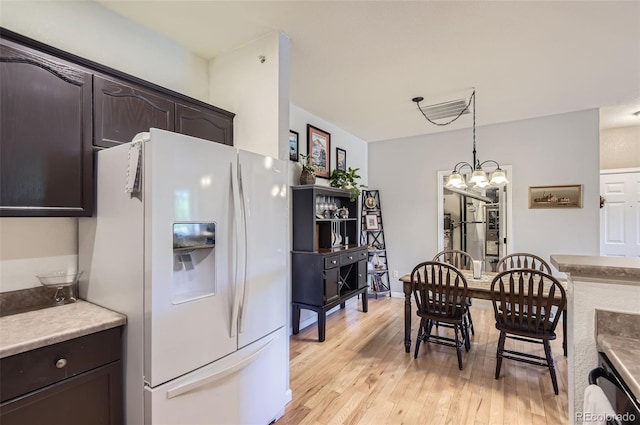 8445 S Holland Way Unit 205, Littleton, CO 80128 - kitchen featuring white fridge with ice dispenser, dark brown cabinets, light wood-type flooring, and decorative light fixtures