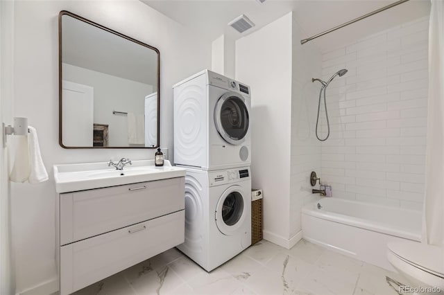 947 S Yates St, Denver, CO 80219 - full bath with stacked washer / dryer, marble finish flooring, toilet, vanity, and bathtub / shower combination