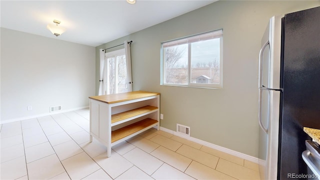 interior space featuring stainless steel refrigerator and light tile patterned floors