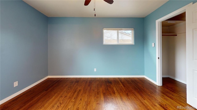 unfurnished bedroom with hardwood / wood-style floors, ceiling fan, a walk in closet, and a closet