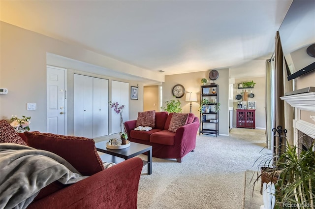 living area featuring baseboards, light carpet, and a fireplace