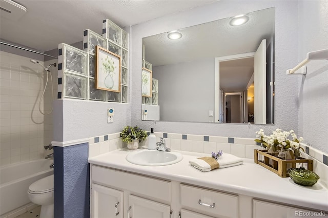 full bath featuring vanity,  shower combination, a textured ceiling, toilet, and a textured wall