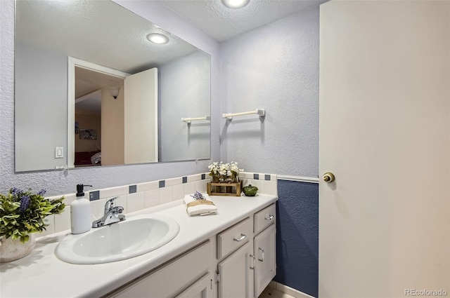 bathroom featuring vanity, a textured wall, backsplash, and a textured ceiling