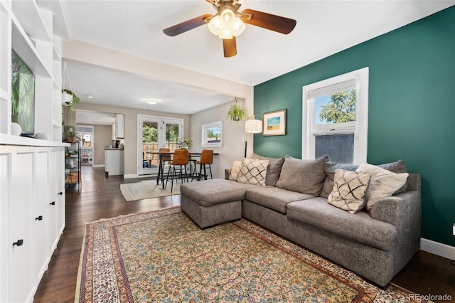 living area featuring baseboards, ceiling fan, and dark wood-style flooring