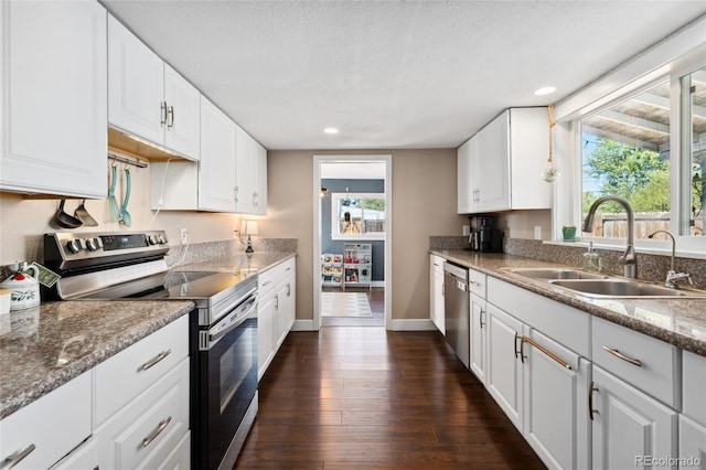 kitchen with a sink, appliances with stainless steel finishes, dark wood finished floors, and white cabinetry