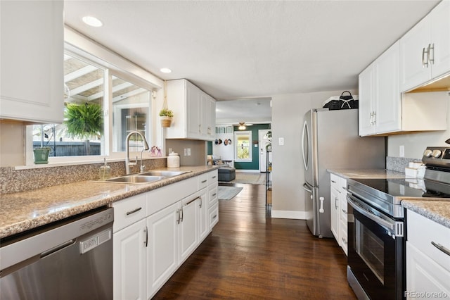 kitchen featuring dark wood-type flooring, light countertops, appliances with stainless steel finishes, white cabinets, and a sink