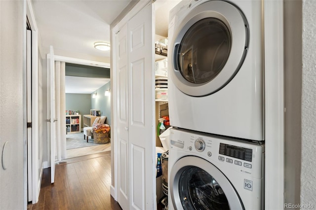 washroom featuring laundry area, stacked washer and clothes dryer, and dark wood-style flooring