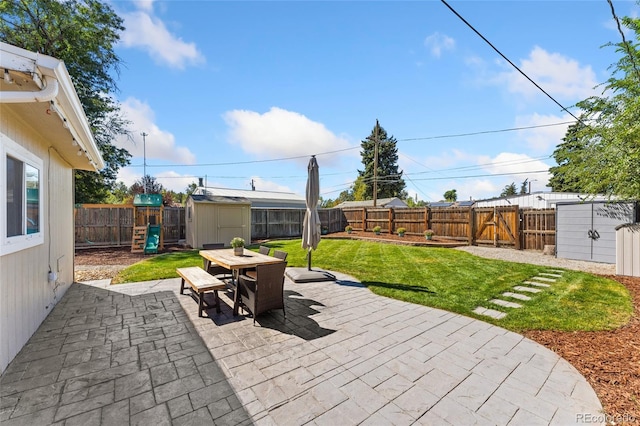 view of patio / terrace featuring a storage unit, an outbuilding, a fenced backyard, and outdoor dining space