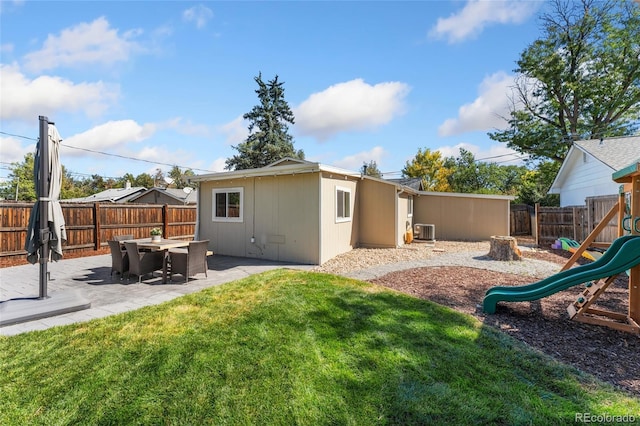 back of property featuring a patio area, a playground, a fenced backyard, and a lawn