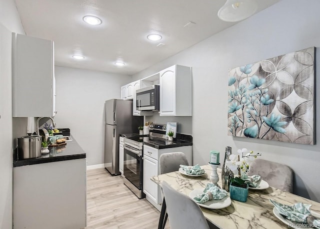8330 Zuni St Unit 116, Denver, CO 80221 - kitchen with stainless steel appliances, white cabinetry, dark countertops, light wood-style flooring, and recessed lighting