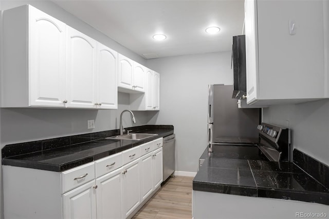 8330 Zuni St Unit 116, Denver, CO 80221 - kitchen featuring appliances with stainless steel finishes, white cabinets, light wood-style flooring, tile countertops, and recessed lighting