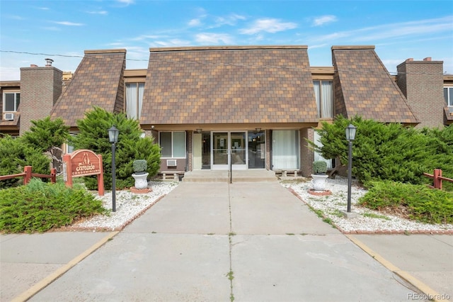 8330 Zuni St Unit 116, Denver, CO 80221 - view of front of property featuring a porch, mansard roof, brick siding, and a shingled roof
