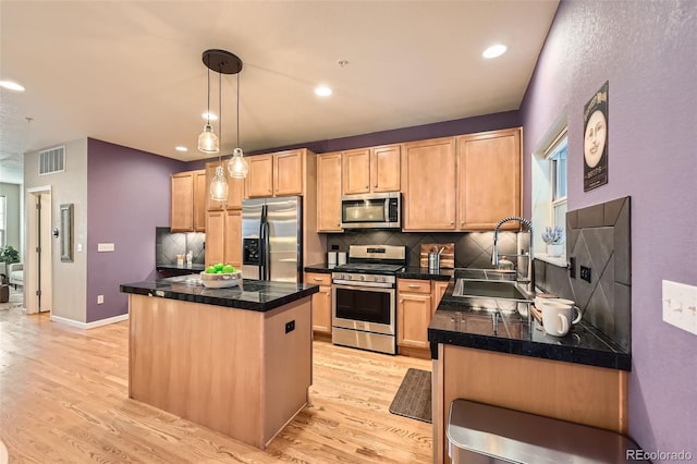 kitchen featuring visible vents, light brown cabinets, a kitchen island, stainless steel appliances, and a sink