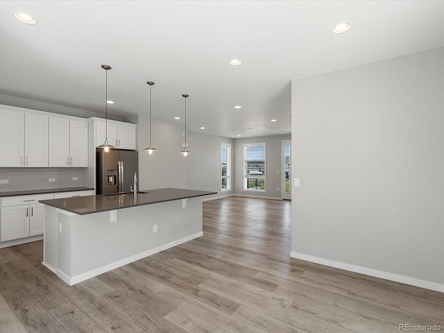3654 Penang Dr, Castle Rock, CO 80109 - kitchen featuring stainless steel refrigerator with ice dispenser, dark countertops, recessed lighting, light wood finished floors, and open floor plan