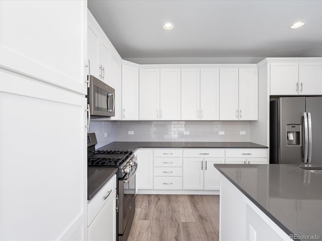 3654 Penang Dr, Castle Rock, CO 80109 - kitchen featuring appliances with stainless steel finishes, dark countertops, white cabinets, light wood-type flooring, and recessed lighting