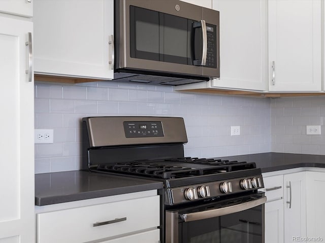 3654 Penang Dr, Castle Rock, CO 80109 - kitchen featuring appliances with stainless steel finishes, dark countertops, white cabinetry, and decorative backsplash