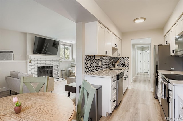 17630 E Loyola Dr Unit 1812L, Aurora, CO 80013 - kitchen with appliances with stainless steel finishes, light wood finished floors, white cabinetry, and a brick fireplace