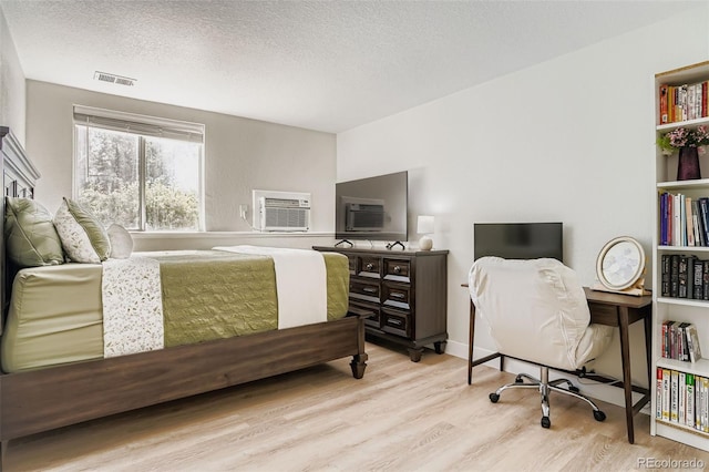 17630 E Loyola Dr Unit 1812L, Aurora, CO 80013 - bedroom featuring wood finished floors, a wall mounted AC, and a textured ceiling